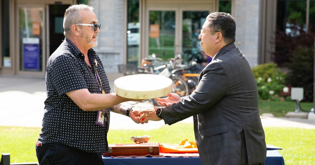 Two men standing outdoors around three feet apart.