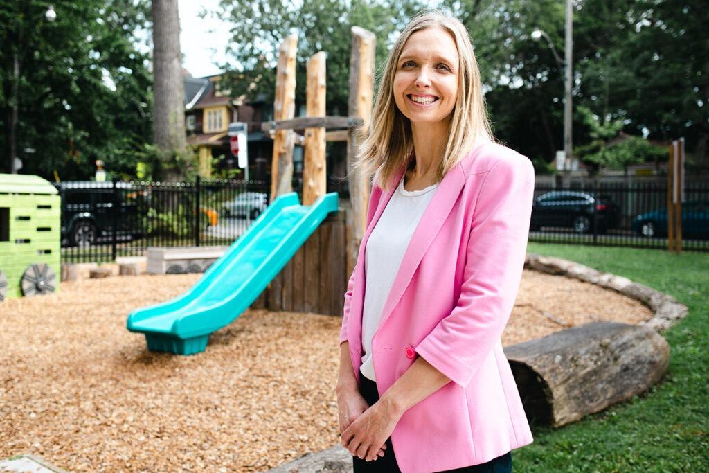 Dr. Anne Wormsbecker stands near a children's play area including a slide.