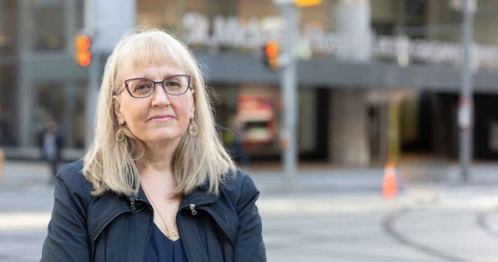 Dr. Sharon Straus stands in front of the Peter Gilgan Patient Care Tower at St. Michael's Hospital.