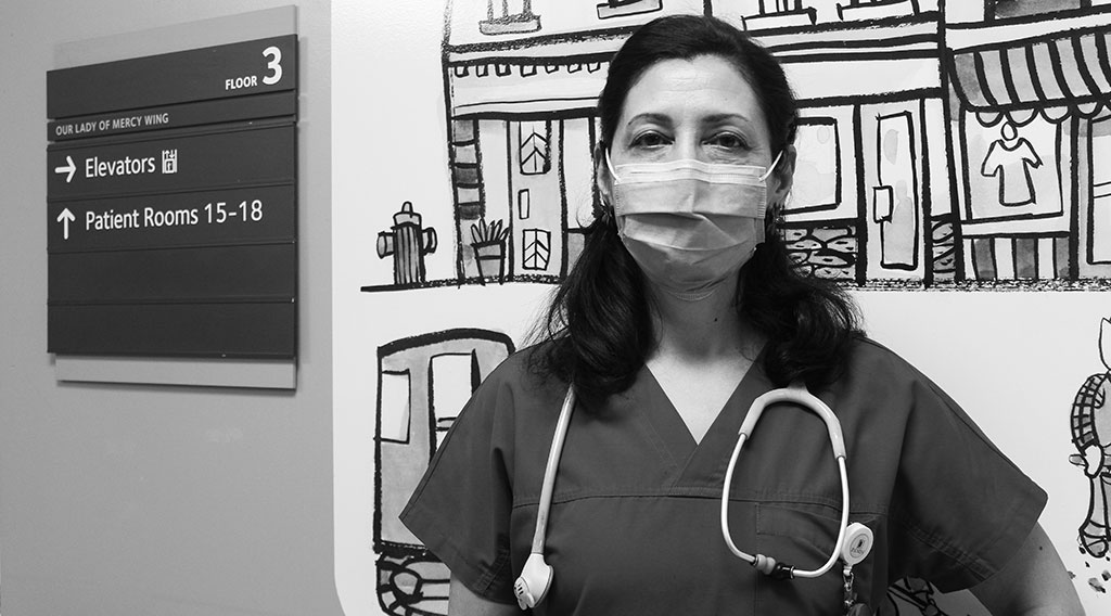 Mahasti Shahlaie Moghaddan, wearing scrubs and a surgical mask, stands in the pediatric wing at St. Joseph's.