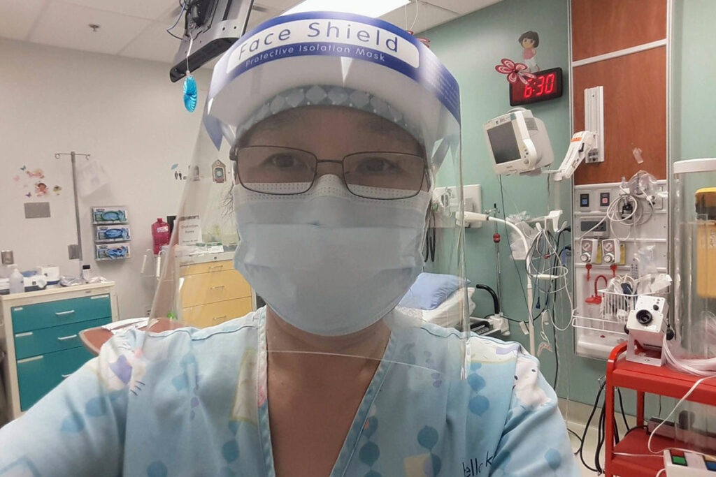 Jenny Jian, wearing hospital scrubs, face mask and face shield.