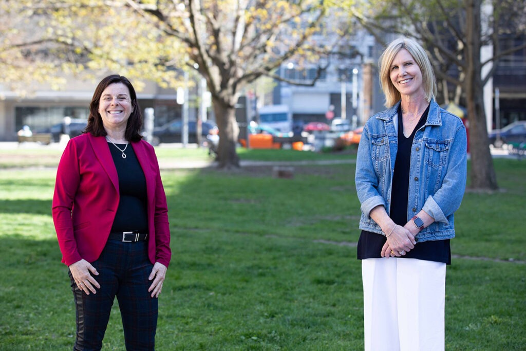 Dr. Karen Weyman and Dr. Daphne Williams stand in a park across the street from St. Michael's Hospital.