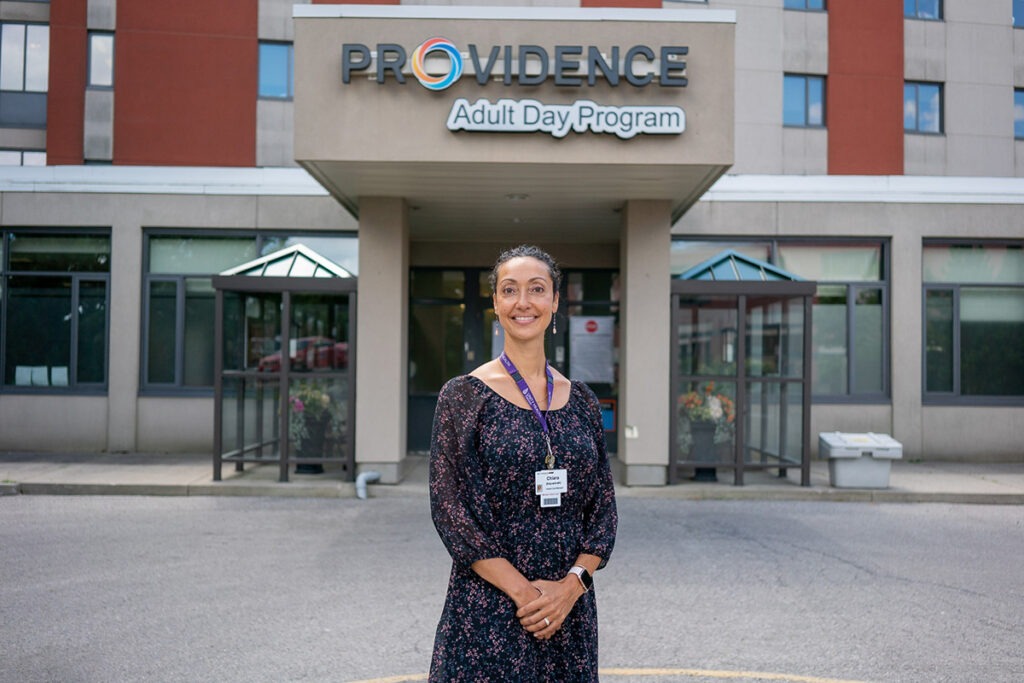 Chiara Campitelli-Thompson stands in front of the entrance to the Providence Adult Day Program.