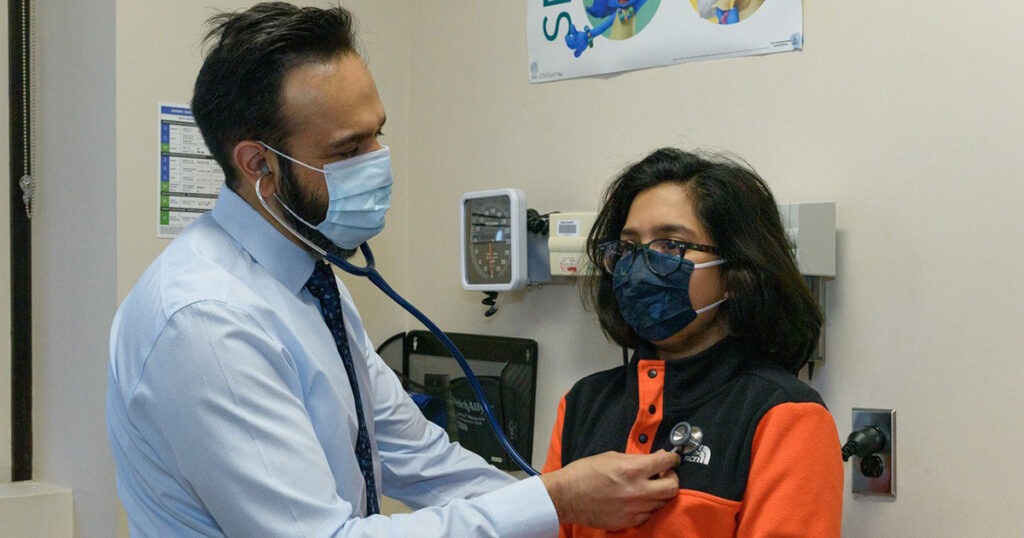 Dr. Ripudaman Minhas uses a stethoscope during a patient check-up.