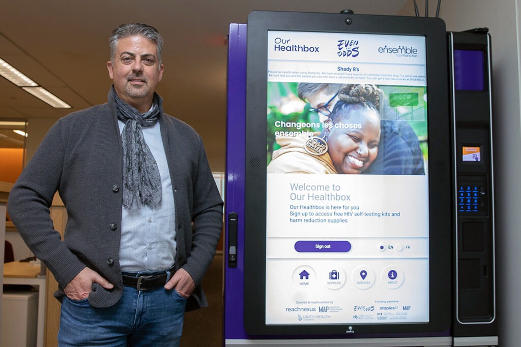 Dr. Sean B. Rourke stands beside an Our Healthbox machine.