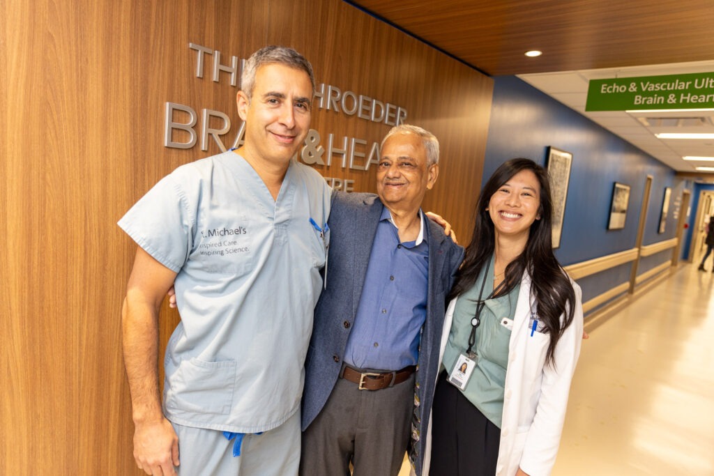 Dr. Neil Fam, patient Mir Hasan Ali and Dr. Geraldine Ong stand in the hallway of the Shroeder Brain & Heart Centre.